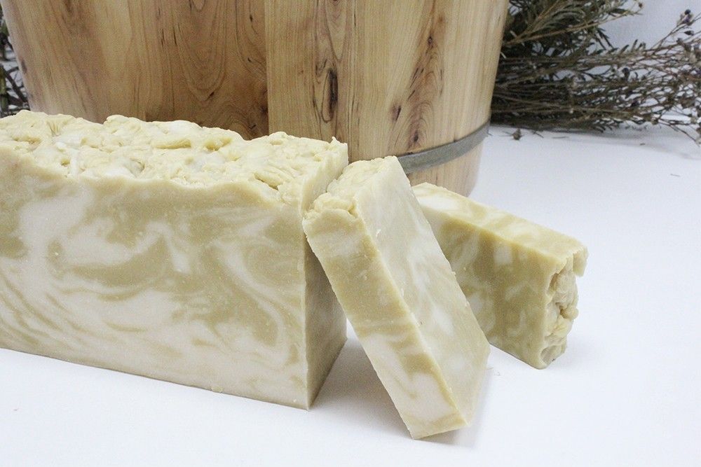 A handcrafted light-tan artisan soap slice showing natural textures from organic argan and olive oil.