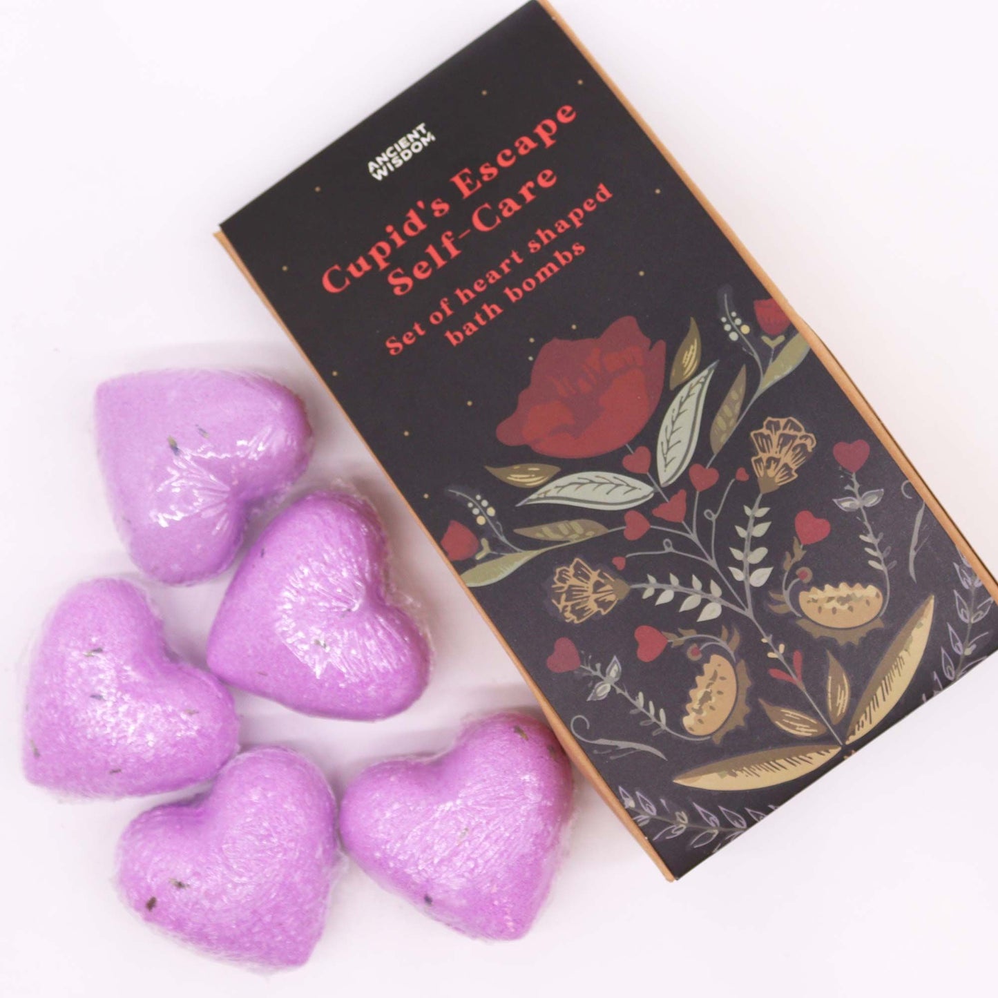 A gift box containing multiple pink and red heart-shaped bath bombs, branded as Cupid's Escape Self Care.