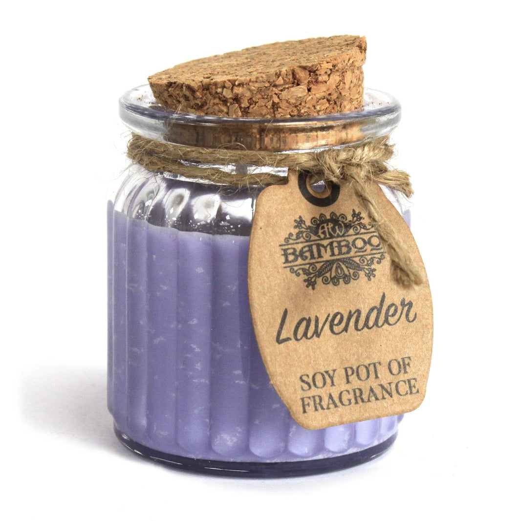 A small clear glass candle jar with purple wax, a cork lid, and a tag showing hand-drawn lavender stems.