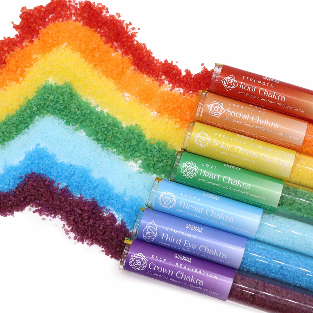 Seven individual tubes of brightly colored bath salts arranged in a rainbow spectrum inside a premium black gift box.
