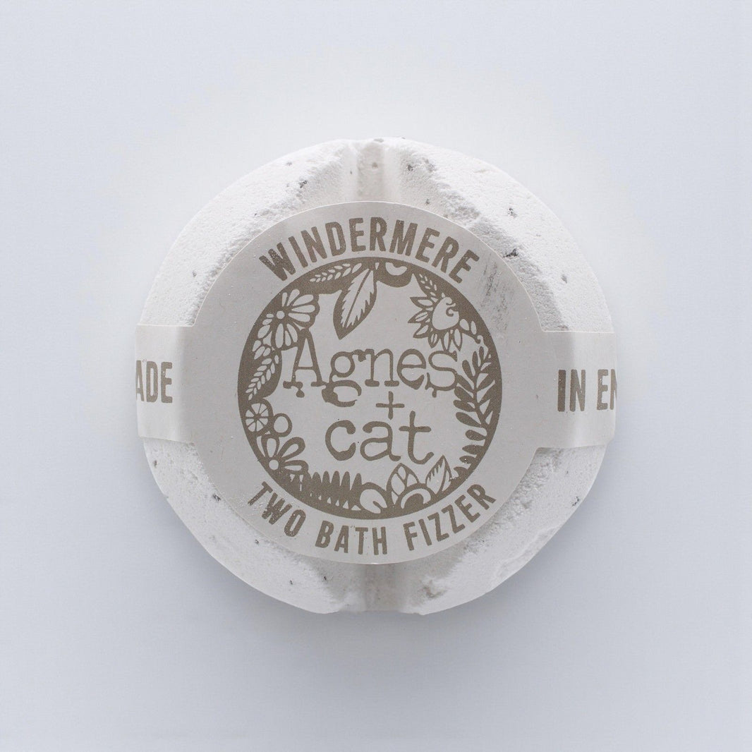 A large, elegant white bath fizzer wrapped in clear protective film with a classic blue and white label.