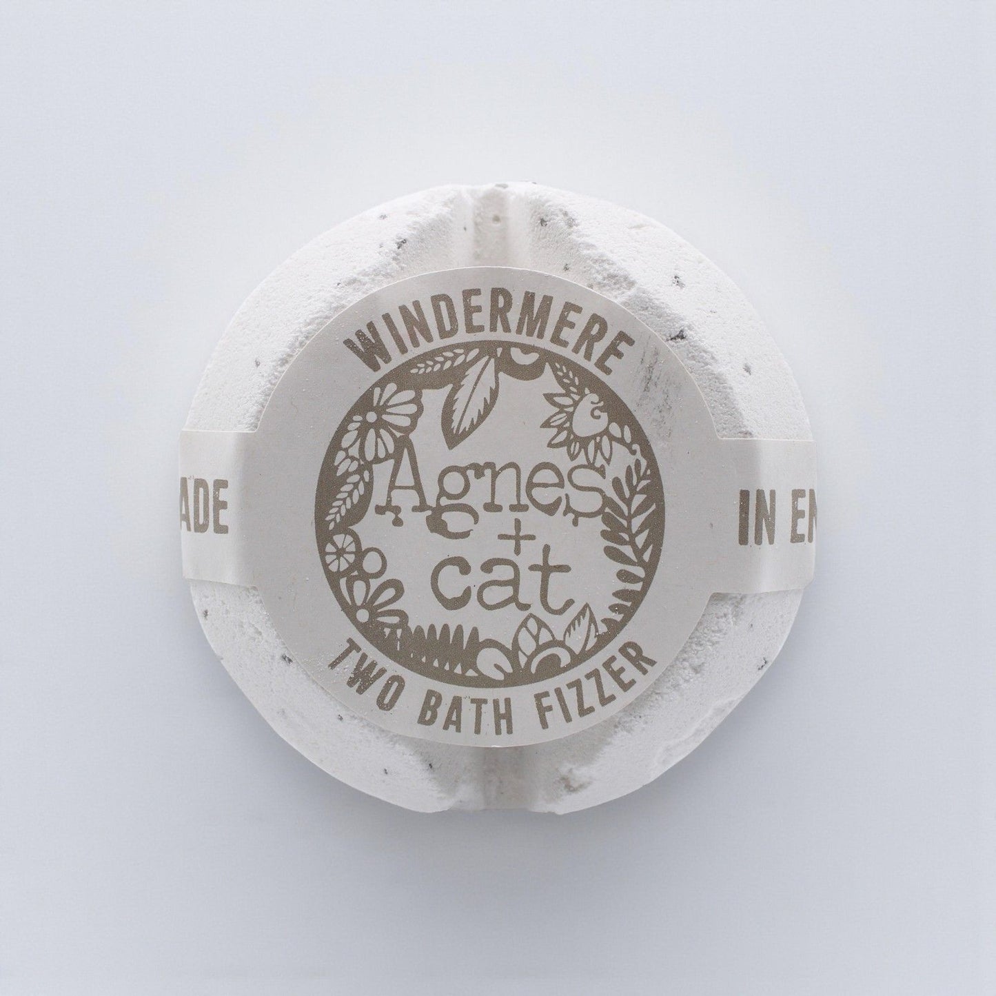 A large, elegant white bath fizzer wrapped in clear protective film with a classic blue and white label.