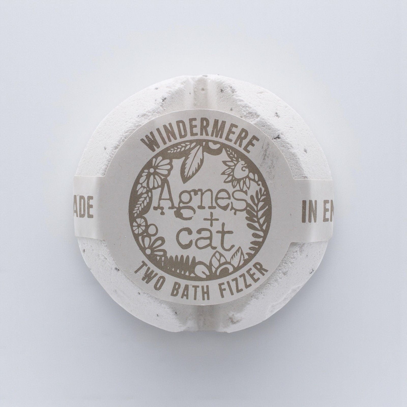 A large, elegant white bath fizzer wrapped in clear protective film with a classic blue and white label.