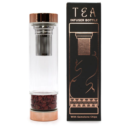 A premium glass infuser bottle with rose gold metallic caps and a base compartment filled with polished red jasper gemstones.