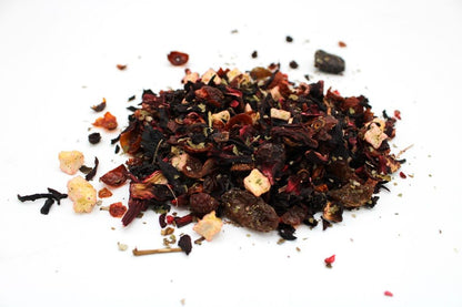 A large quantity of loose-leaf herbal tea featuring dark leaves, twigs, and dried berries reminiscent of a forest floor.