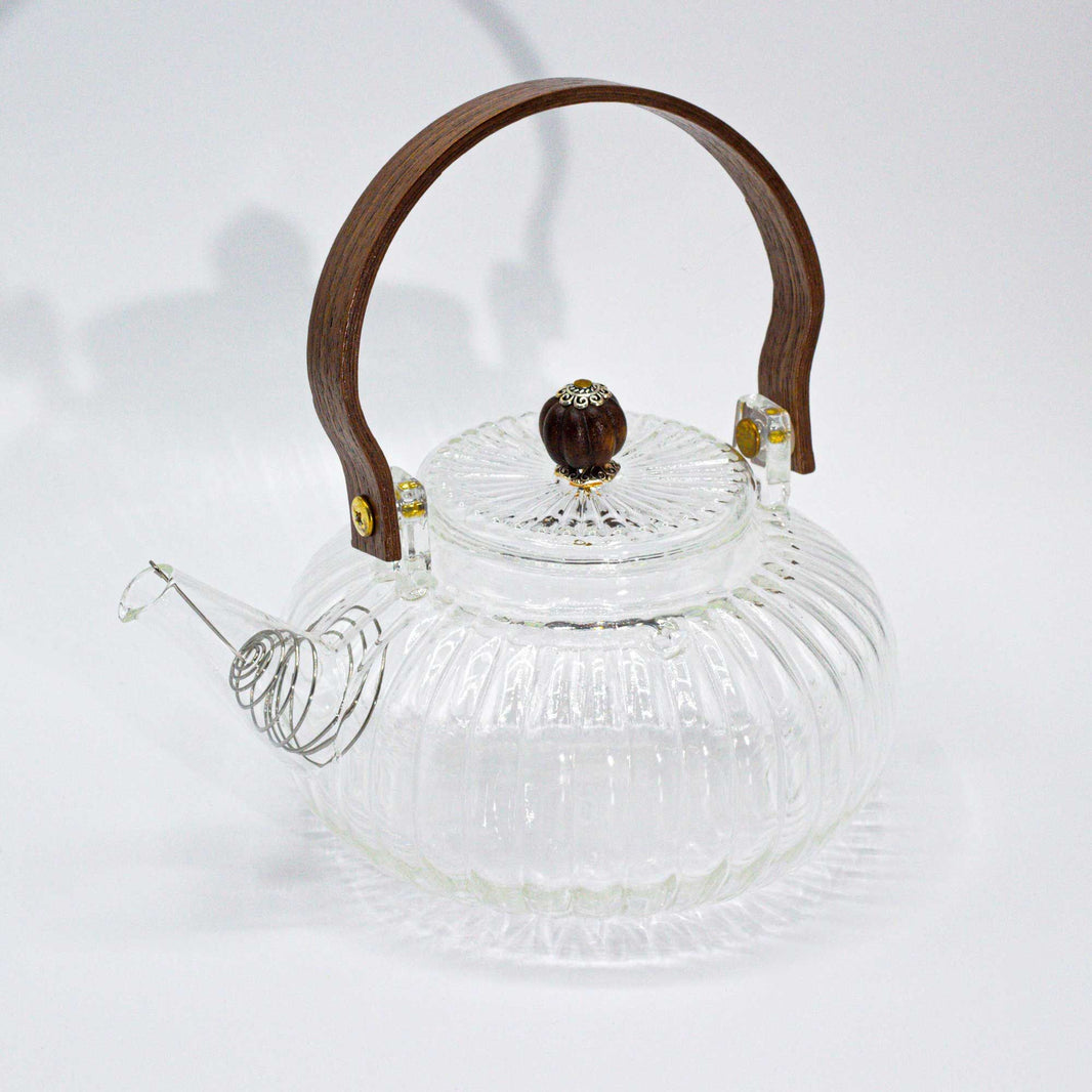 A medium-sized round glass teapot with vertical ribbed texture and a traditional curved glass handle.