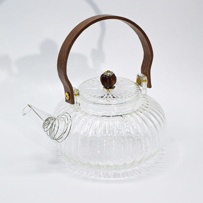 A medium-sized round glass teapot with vertical ribbed texture and a traditional curved glass handle.