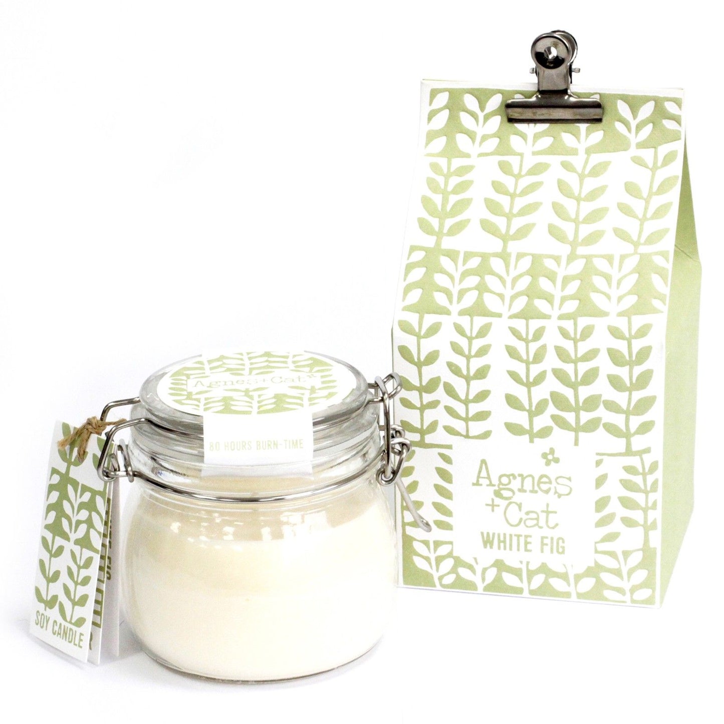 A small glass Kilner jar with a metal clip lid filled with white scented candle wax next to its decorative green tag.