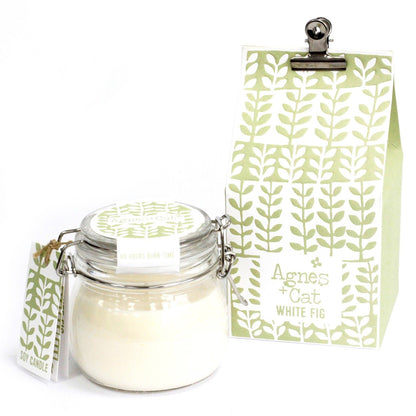 A small glass Kilner jar with a metal clip lid filled with white scented candle wax next to its decorative green tag.