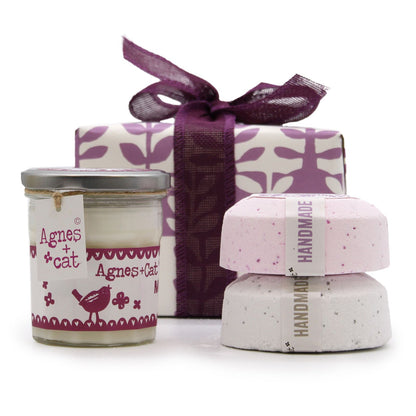 A premium gift box containing a Moonstone candle and botanical-themed bath fizzers with a purple ribbon.