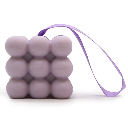 A purple massage soap bar with raised nubs for skin stimulation, scented with Lavender and Lilac, inside its individual box.