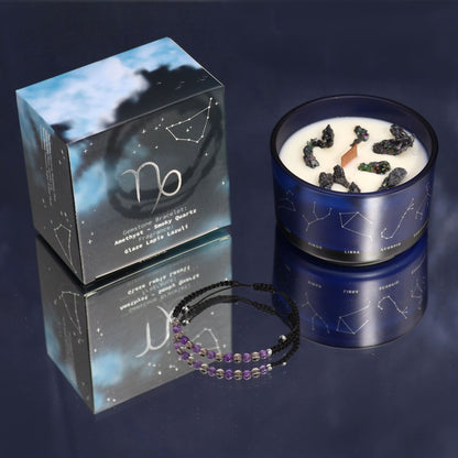 A premium Capricorn zodiac candle in a black tin with gold accents, displayed with its hidden gemstone bracelet.