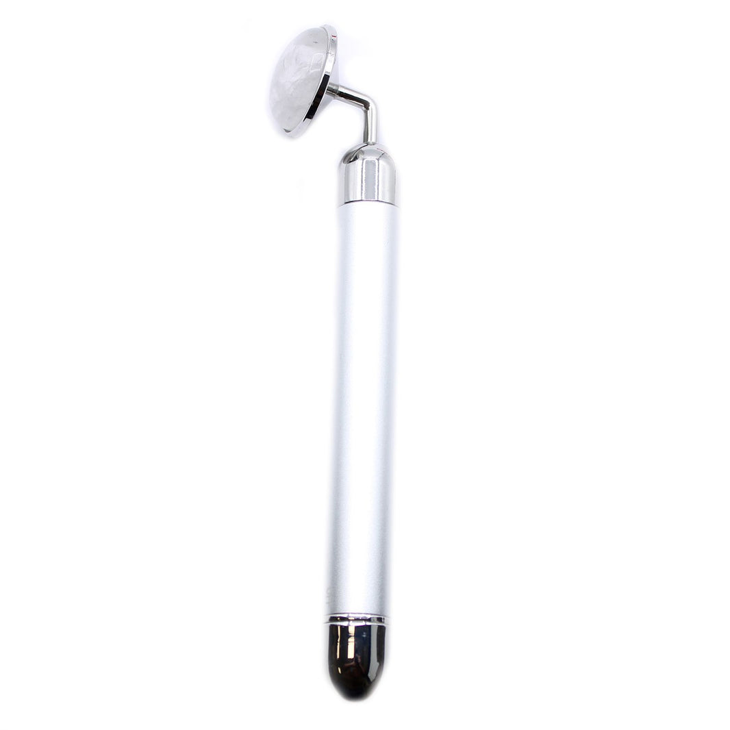 A polished clear rock quartz gemstone vibration pad designed for stimulating facial rituals and skincare absorption.