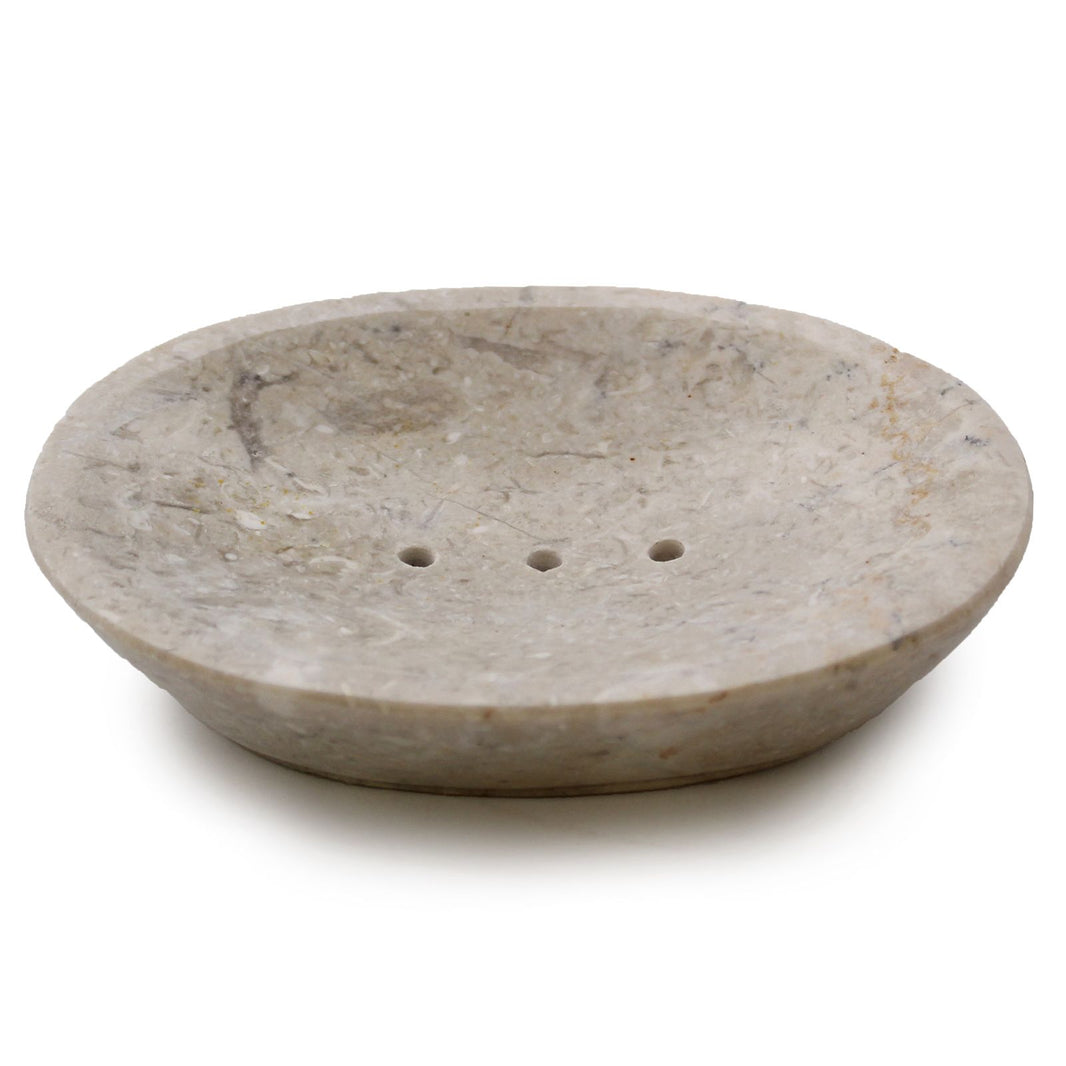 A wide, shallow oval soap dish made from polished cream-colored marble featuring natural dark grey speckles.