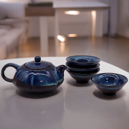 A dark blue ceramic teapot set featuring a textured teapot with a handle and four matching small tea cups.