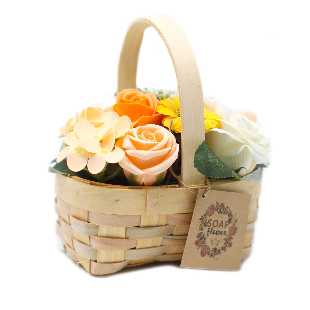 A medium-sized wicker gift basket filled with realistic orange and yellow soap roses and carnations with decorative greenery.