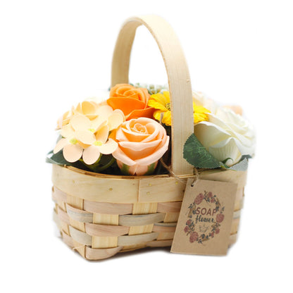 A medium-sized wicker gift basket filled with realistic orange and yellow soap roses and carnations with decorative greenery.