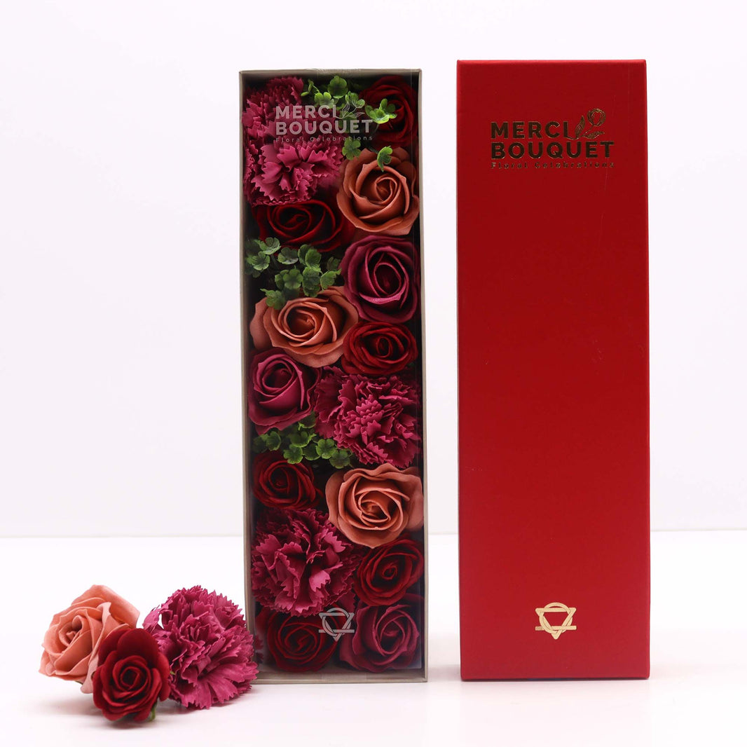 A luxury red long gift box filled with realistic antique-style pink and mauve soap roses arranged in a decorative display.