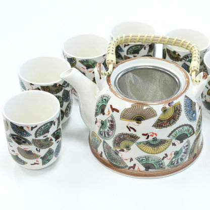 A cream-colored ceramic teapot and matching cups decorated with intricate traditional Chinese fan and flower motifs.
