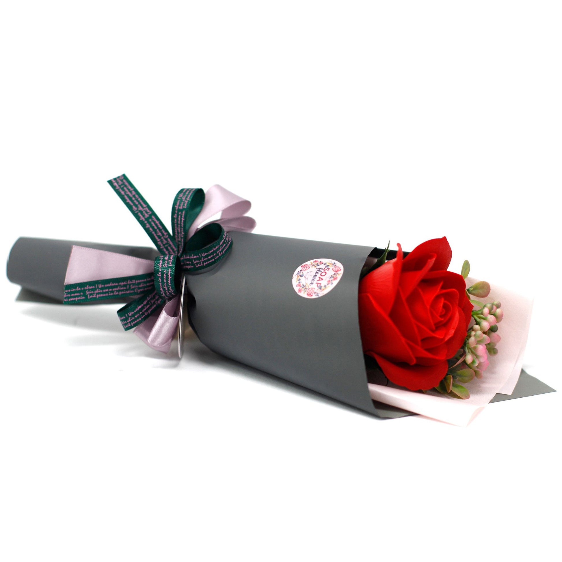 A large, realistic bouquet of red soap roses wrapped in decorative paper with a black and white ribbon.