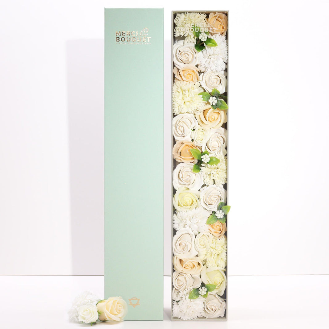 A tall, slender white gift box decorated with elegant gold and floral patterns, containing a selection of premium bath products.