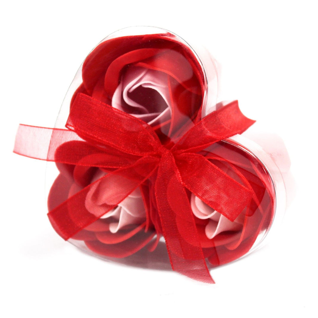 A small heart-shaped red gift box containing three realistic red soap rose flowers.
