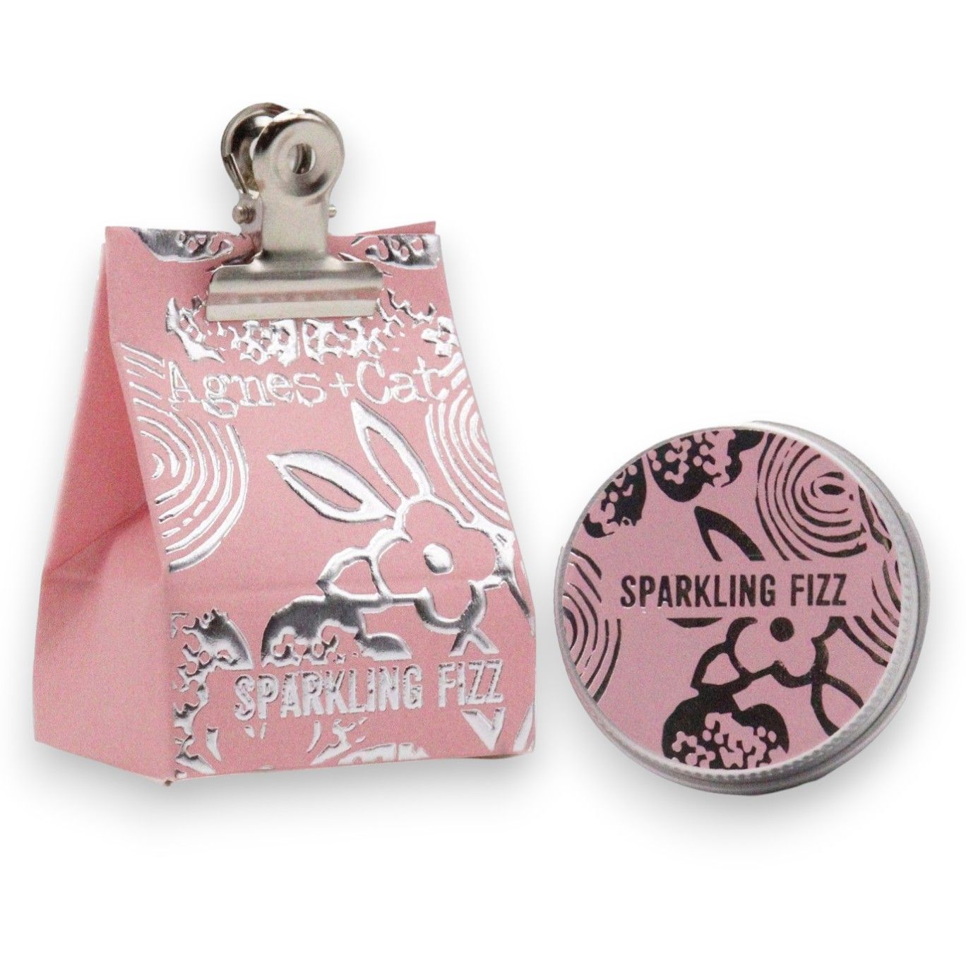 A 20g round tin of Sparkling Fizz scented lip balm shown with its pink and black festive celebration packaging.