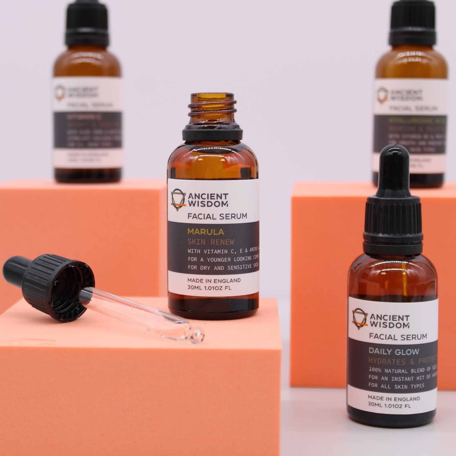 Professional amber glass dropper bottles of facial oil arranged on a minimalist terracotta-toned background.