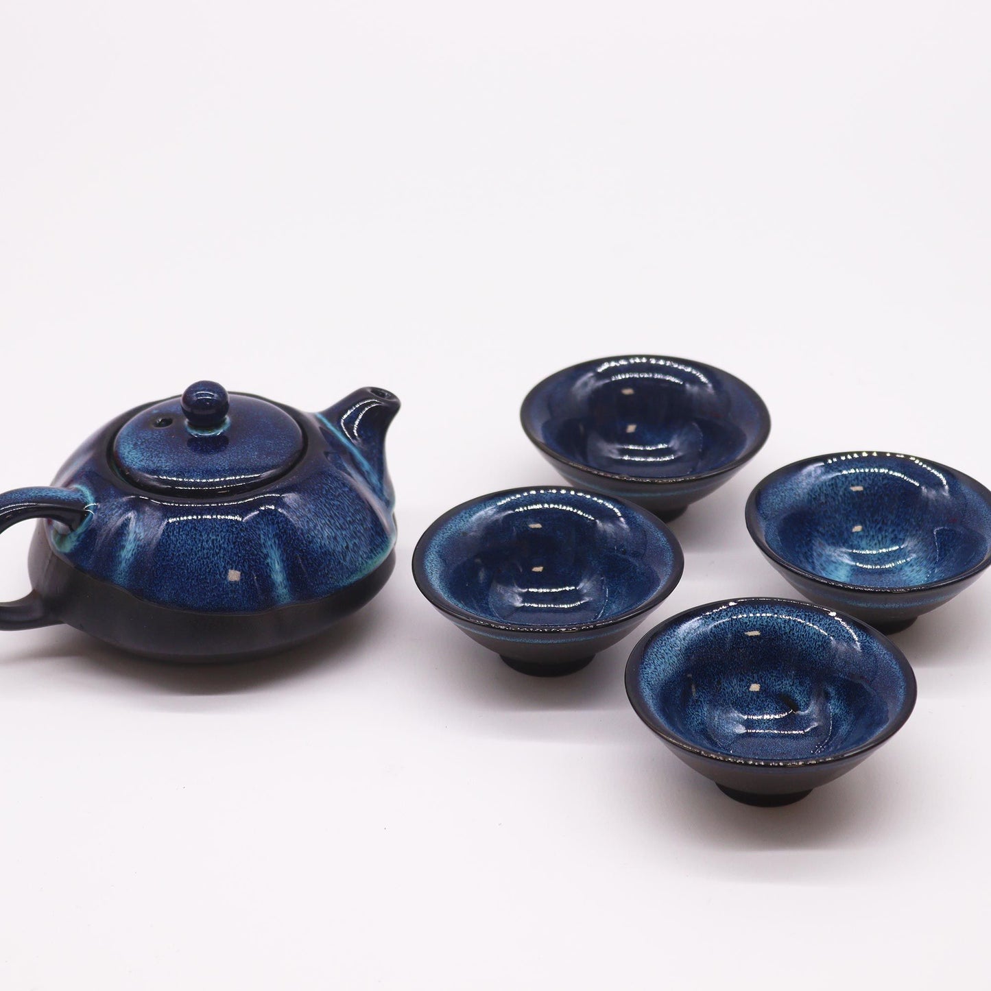 A dark blue ceramic teapot set featuring a textured teapot with a handle and four matching small tea cups.