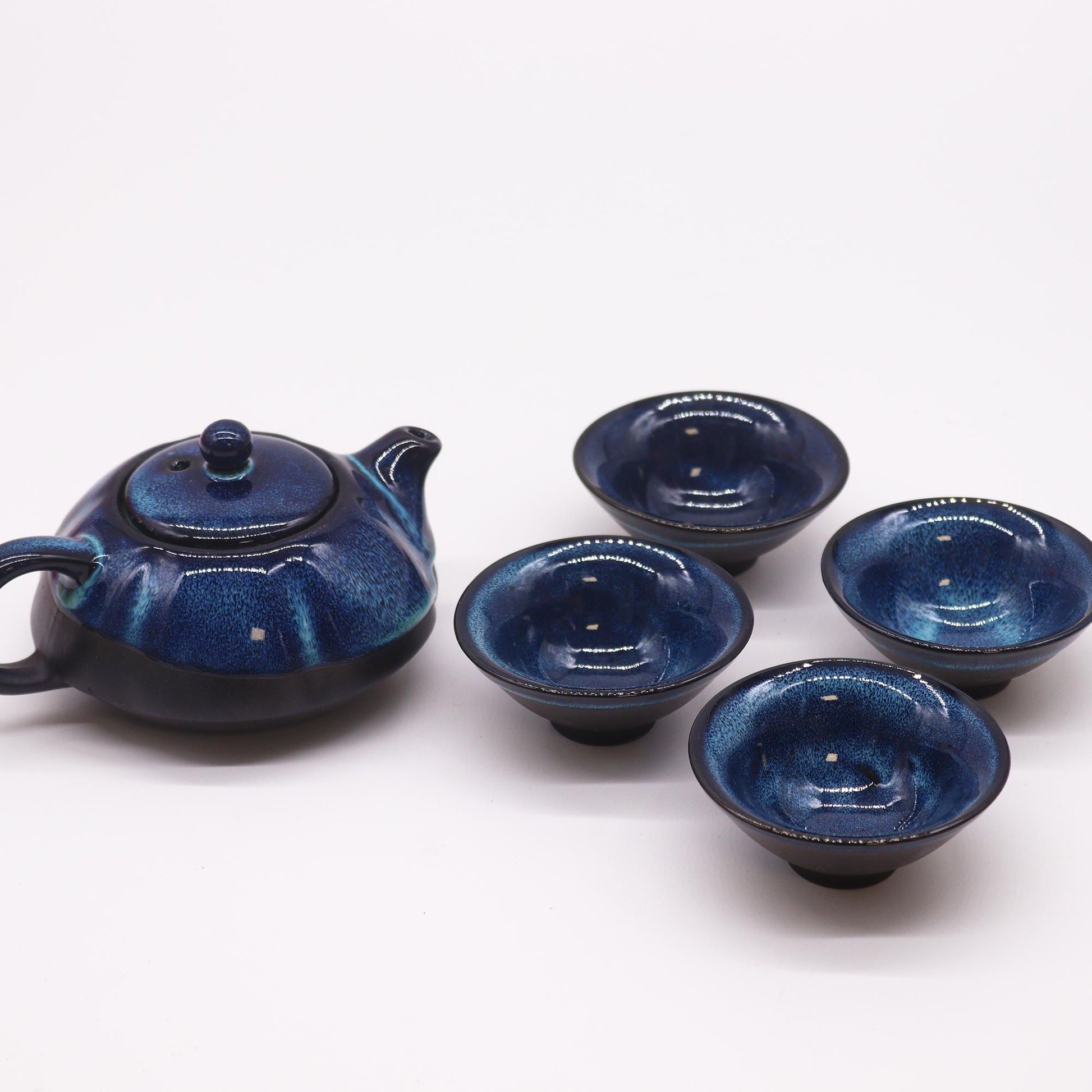 A dark blue ceramic teapot set featuring a textured teapot with a handle and four matching small tea cups.