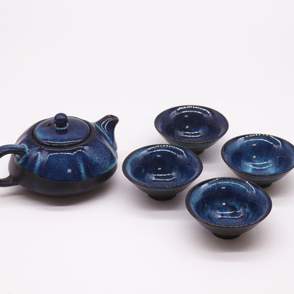 A dark blue ceramic teapot set featuring a textured teapot with a handle and four matching small tea cups.
