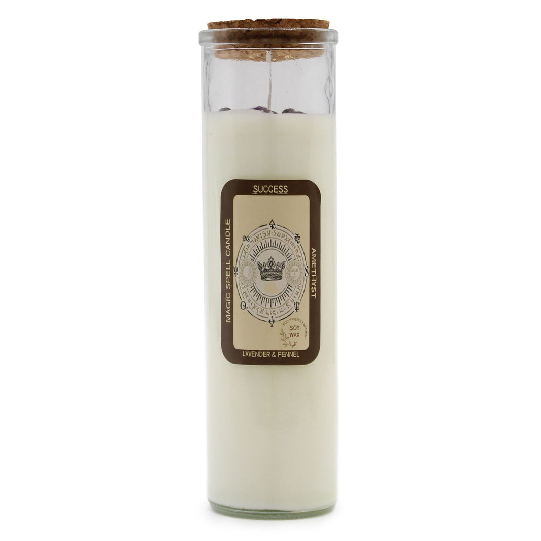 A tall white pillar candle with a 'Success' label featuring gold-toned mystical icons and botanical details.