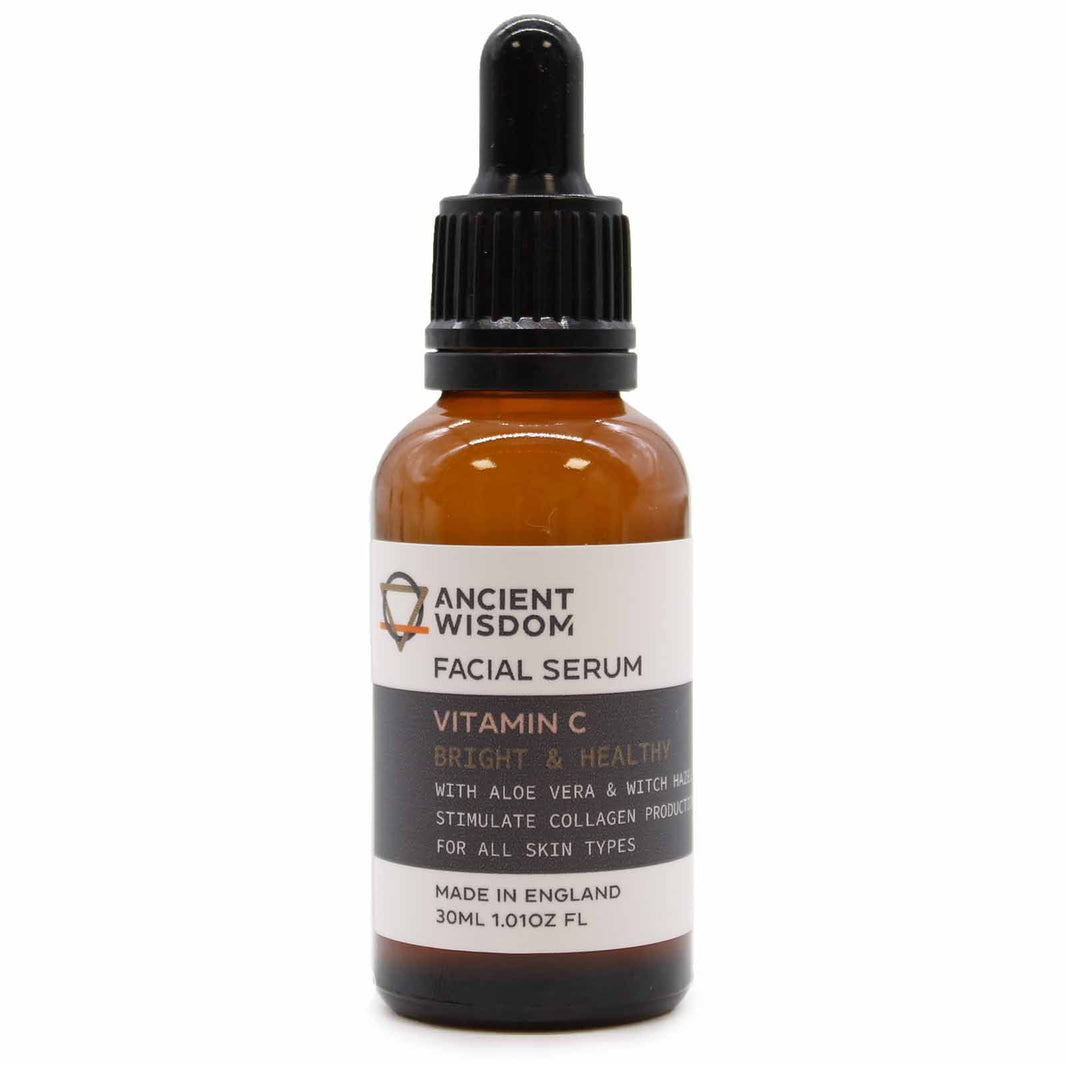 An amber glass bottle of Vitamin C face serum with a professional black dropper top and an apothecary-style label.