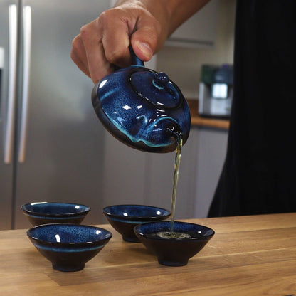 A dark blue ceramic teapot set featuring a textured teapot with a handle and four matching small tea cups.