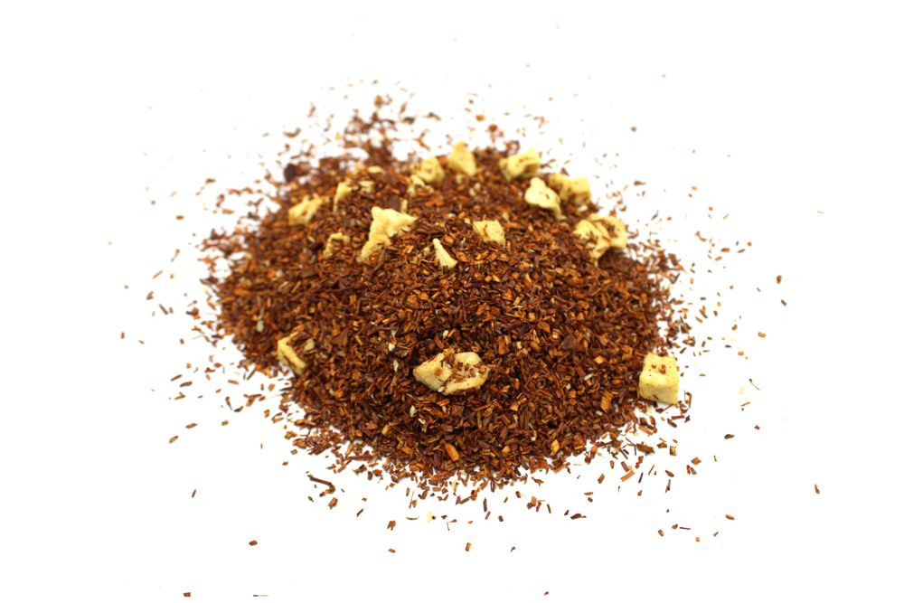 A high-volume display of a diverse herbal tea blend containing various dried fruits, flower petals, and assorted herbal leaves.