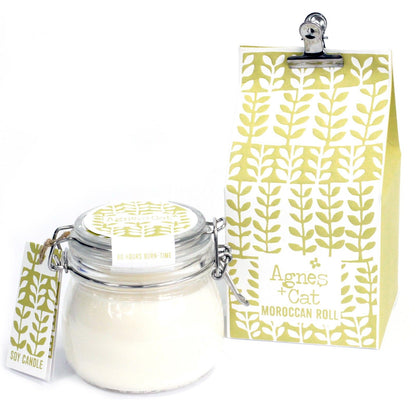 A classic glass preserve jar with a silver clip top containing a hand-poured scented candle and a yellow patterned tag.