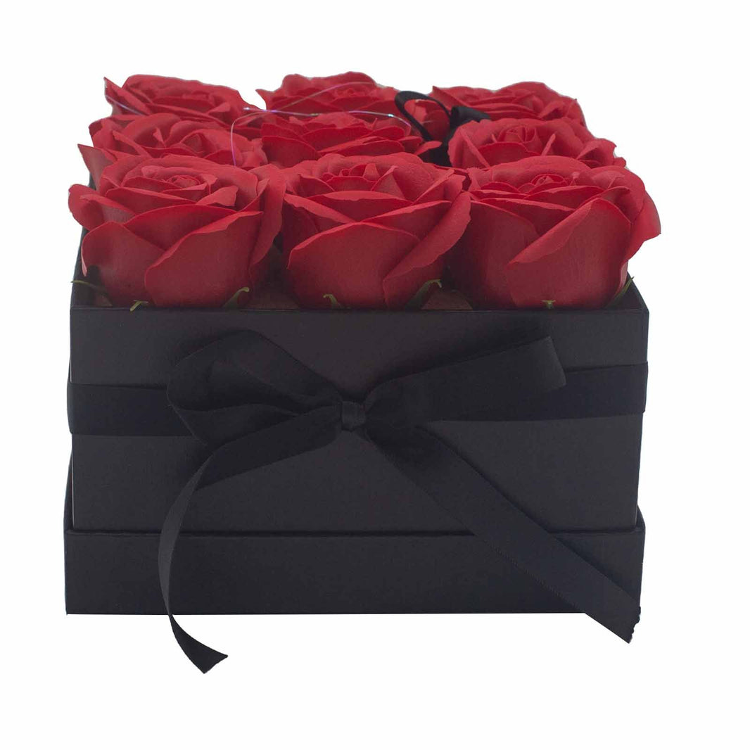 A black square gift box featuring 9 realistic red soap roses arranged in a classic floral display.