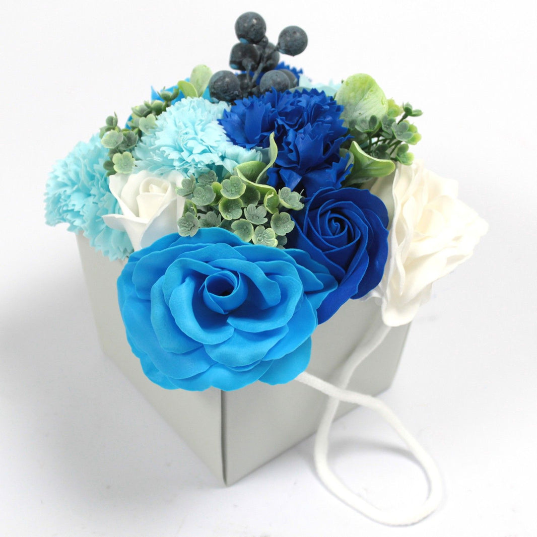 A luxury soap flower bouquet with blue and white roses and carnations in a grey gift box.