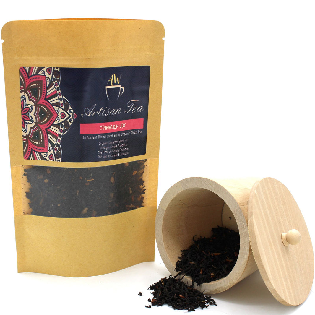 An eco-friendly cardboard tea tube with a minimalist label next to a sample of organic cinnamon-infused black tea.