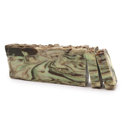 A rustic, brown-toned handcrafted soap slice with visible cinnamon spice grains and a textured, artisanal finish.