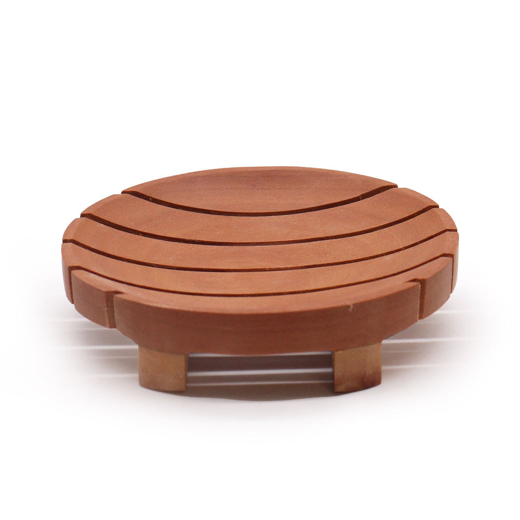 A circular soap holder made from dark, polished mahogany wood with carved horizontal drainage grooves.