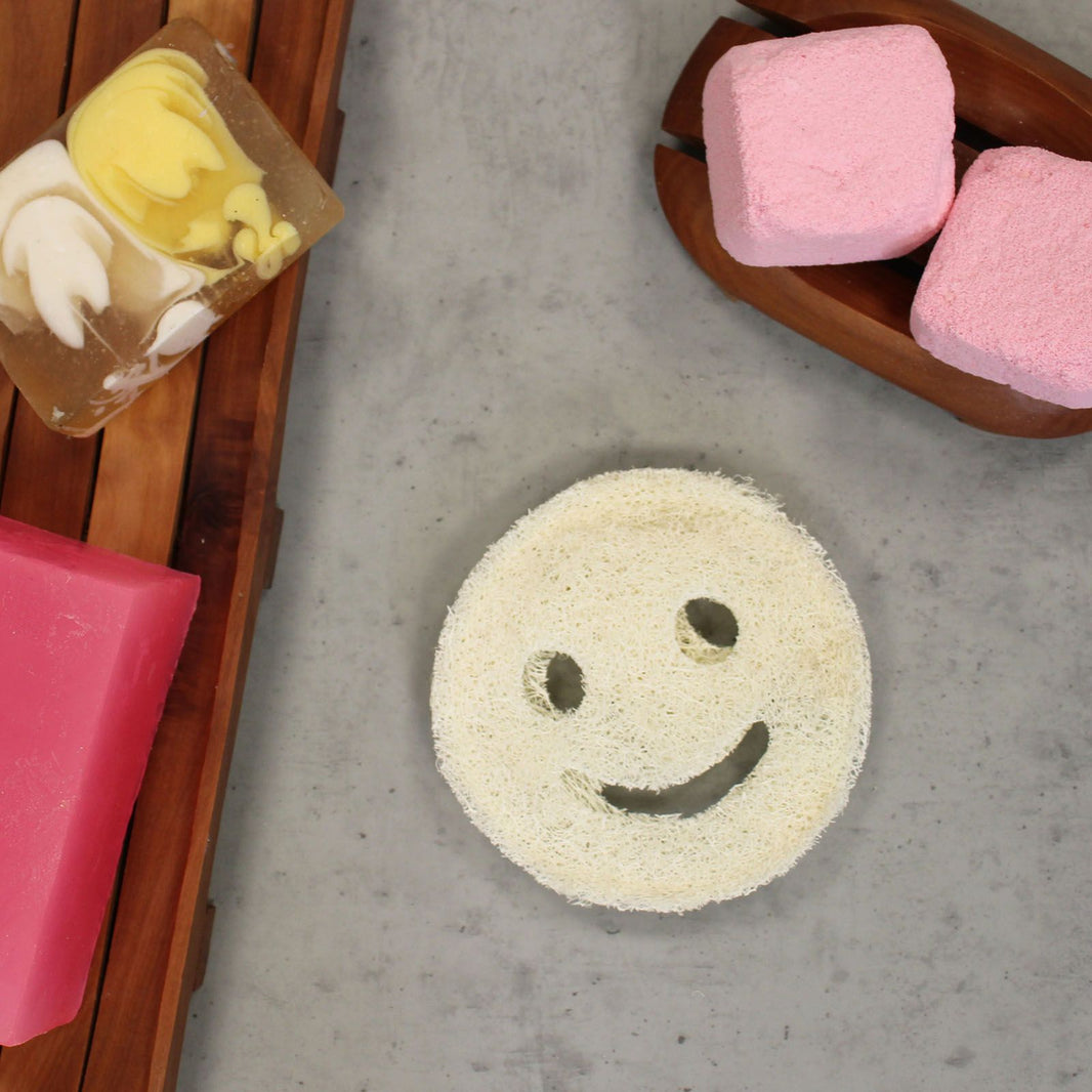 A natural, dried whole loofah sponge carved with a cheerful smiley face for fun and eco-friendly body exfoliation.