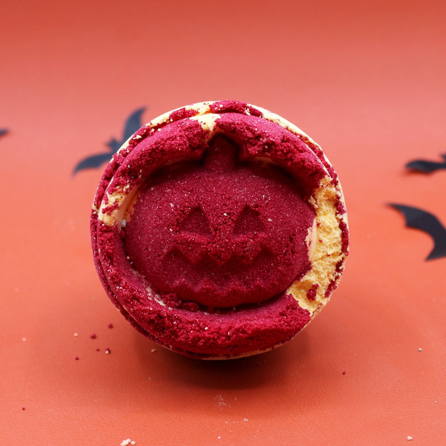 A bright orange, pumpkin-shaped bath bomb with a carved jack-o'-lantern face, perfect for a Halloween bath ritual.