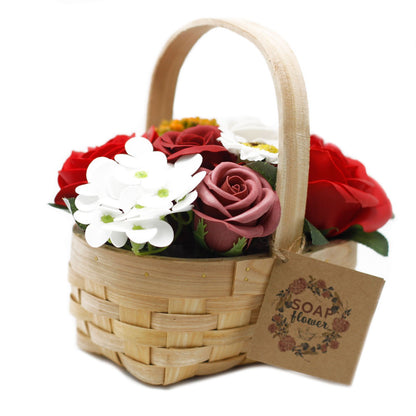 A charming wicker basket containing a lush arrangement of realistic red soap roses and decorative greenery.