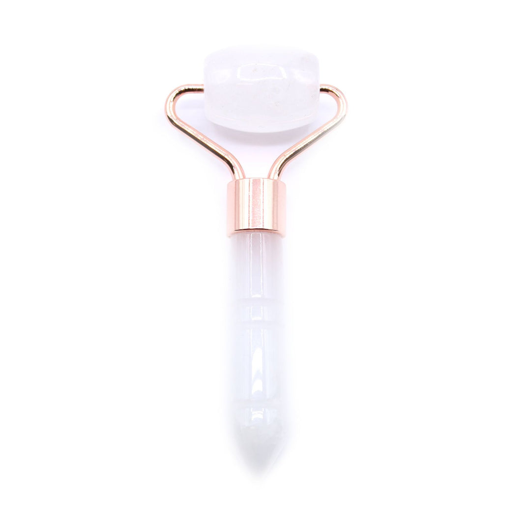 A travel-sized gemstone facial roller made from natural clear rock quartz with a minimalist white handle.
