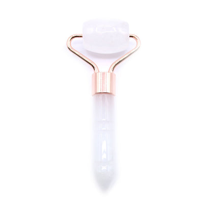 A travel-sized gemstone facial roller made from natural clear rock quartz with a minimalist white handle.