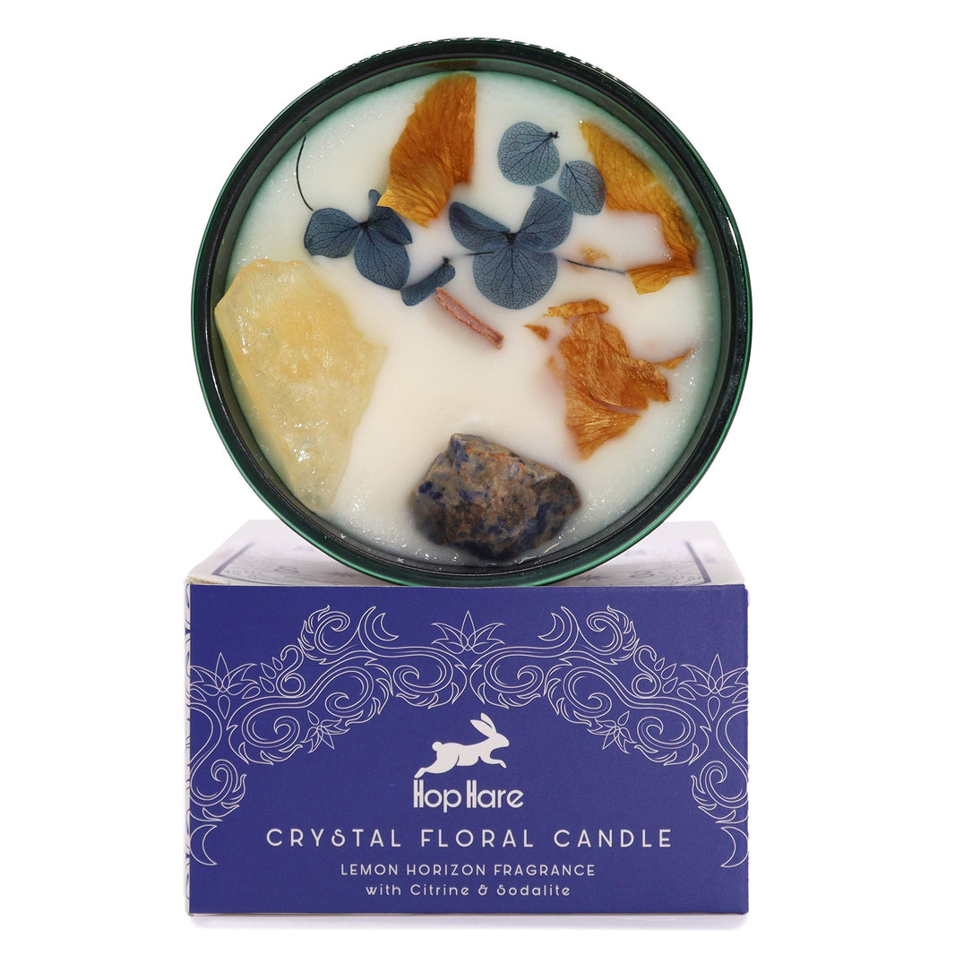 The Sun tarot-inspired crystal candle in a yellow glass jar topped with natural gemstones and bright floral accents.