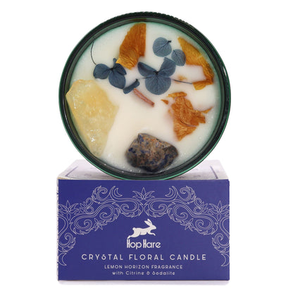 The Sun tarot-inspired crystal candle in a yellow glass jar topped with natural gemstones and bright floral accents.