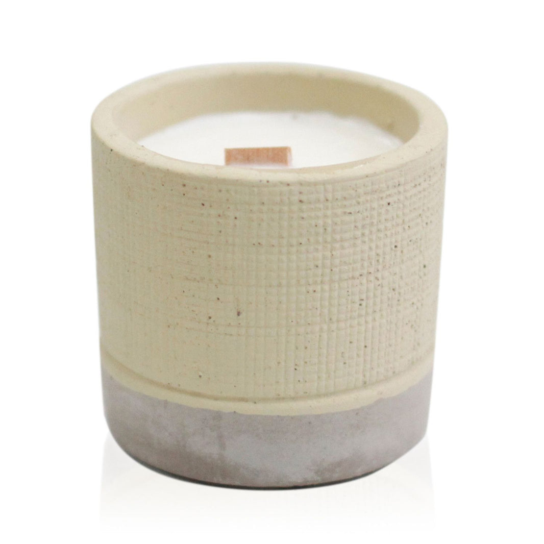 A minimalist grey concrete pot containing a hand-poured soy candle with a smooth, industrial aesthetic.