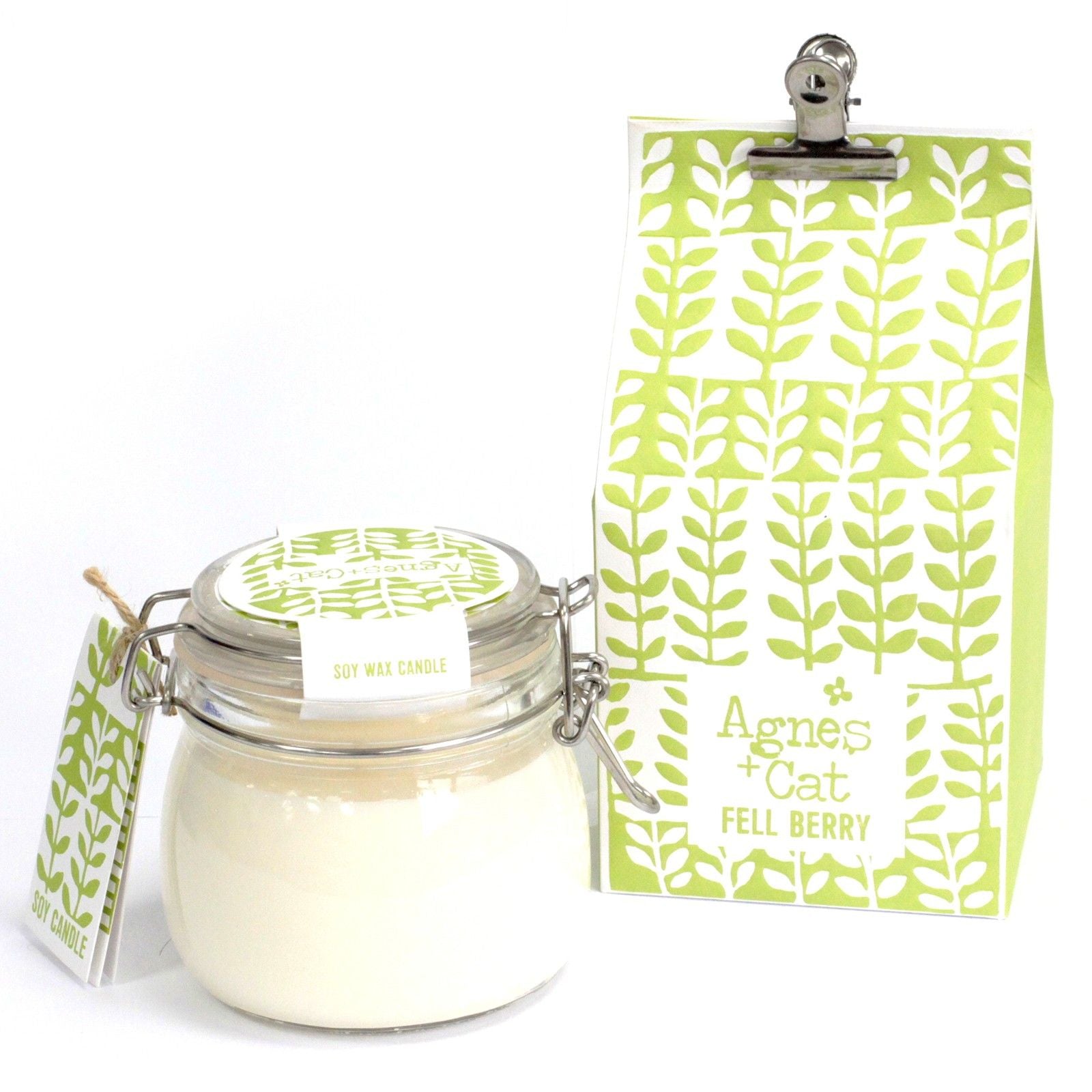 A clear glass preserve-style jar with a metal clip-top lid, housing a white scented candle with a green floral hanging tag.